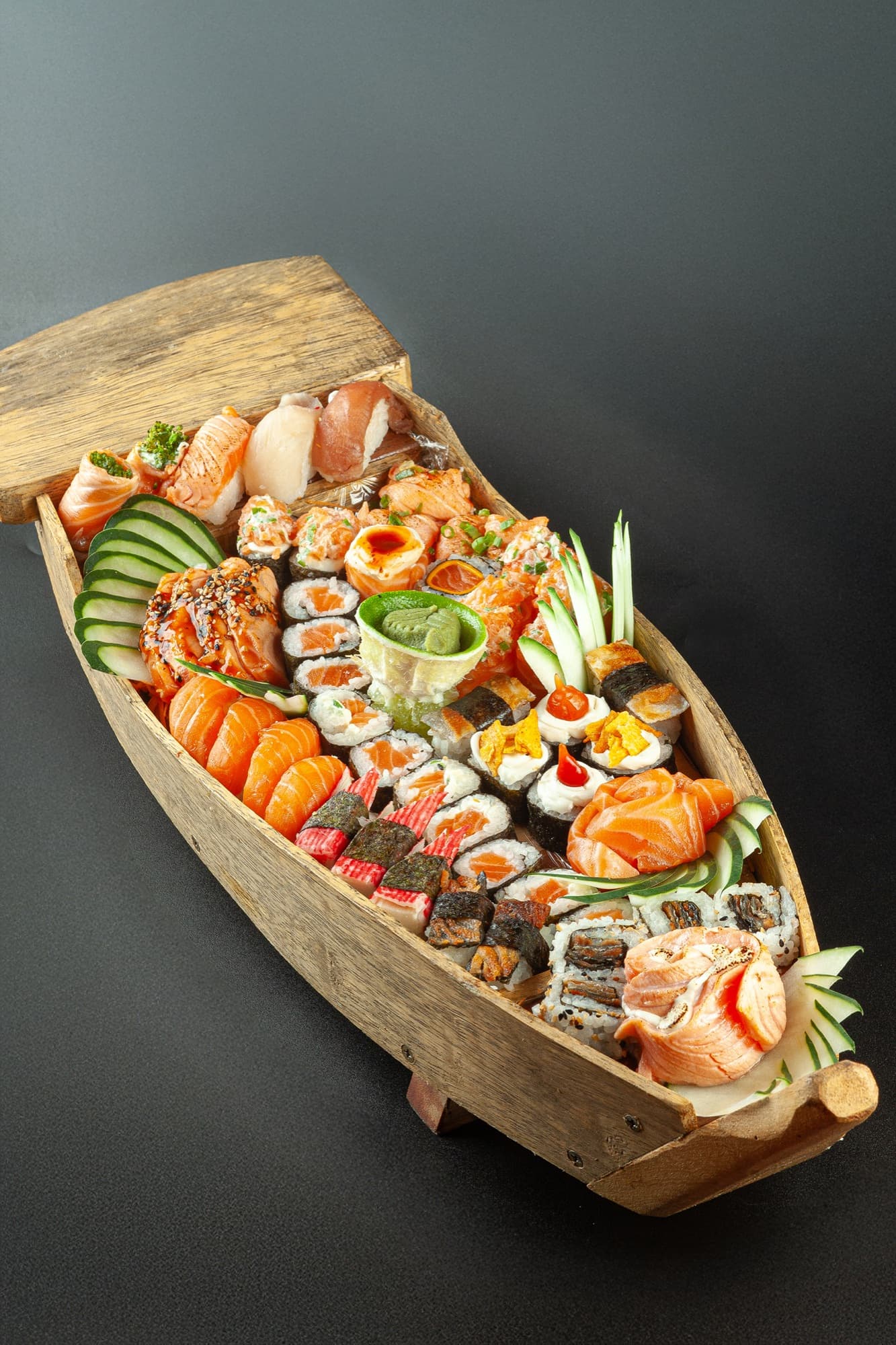 Barca de madeira repleta de sashimis, niguiris, uramakis e hot rolls da casa