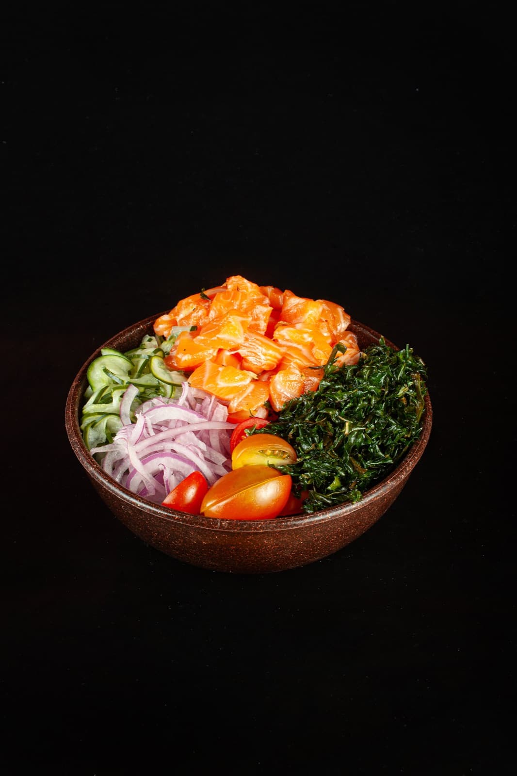 Bowl de poke com cubos de salmão, pepino, cebola-roxa, tomate e couve crispy