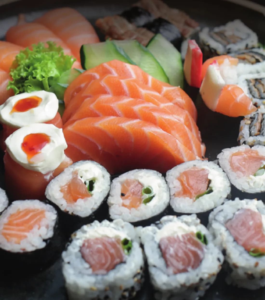 Sashimis de salmão, niguiris e uramakis em travessa preta