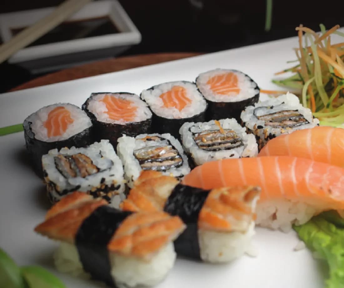Prato com makis de salmão, uramakis e niguiris sobre travessa branca