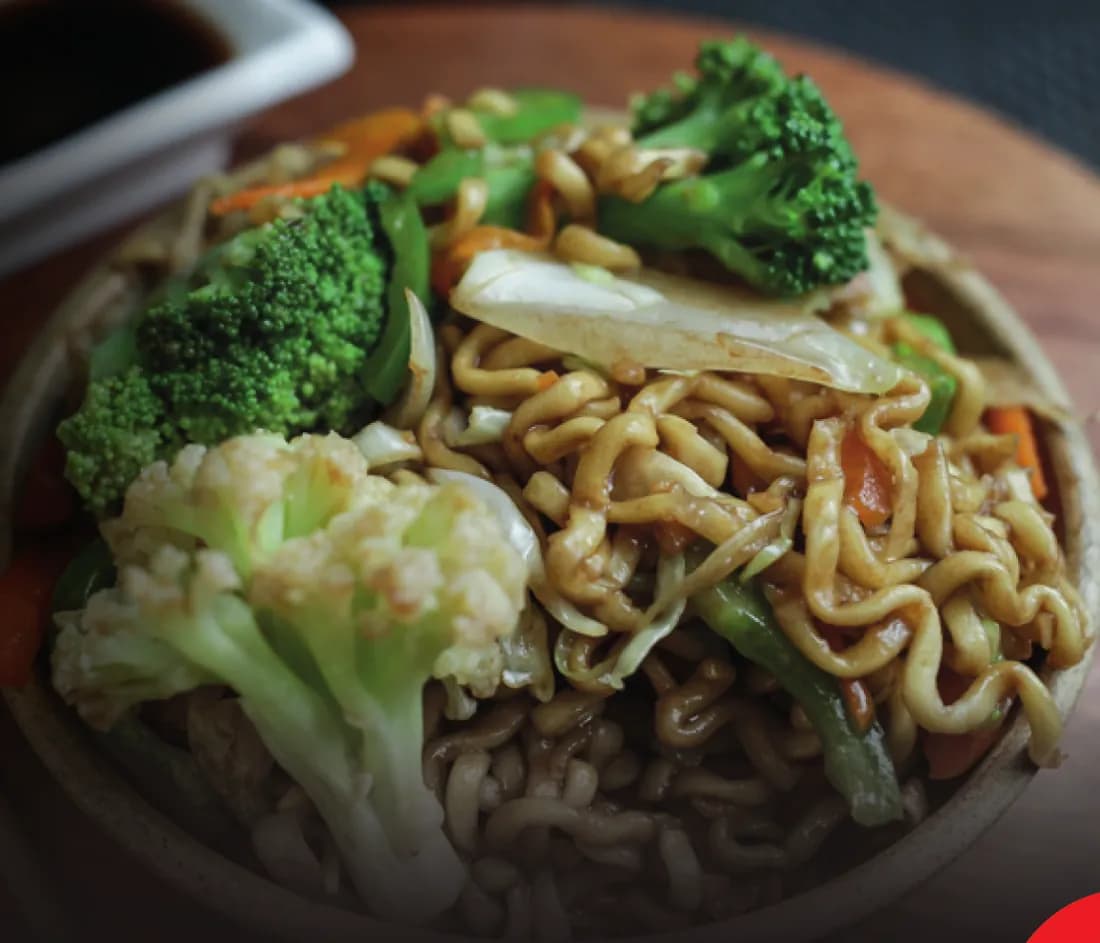 Yakissoba com brócolis, couve-flor e legumes em prato de barro