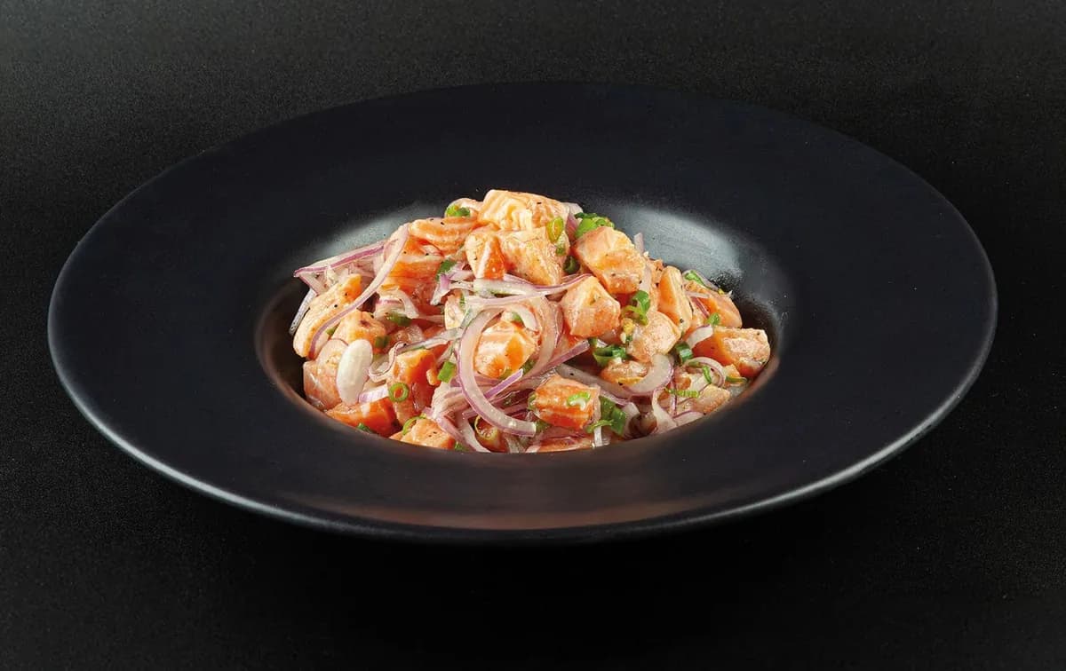 Ceviche de salmão com cebola roxa em prato preto