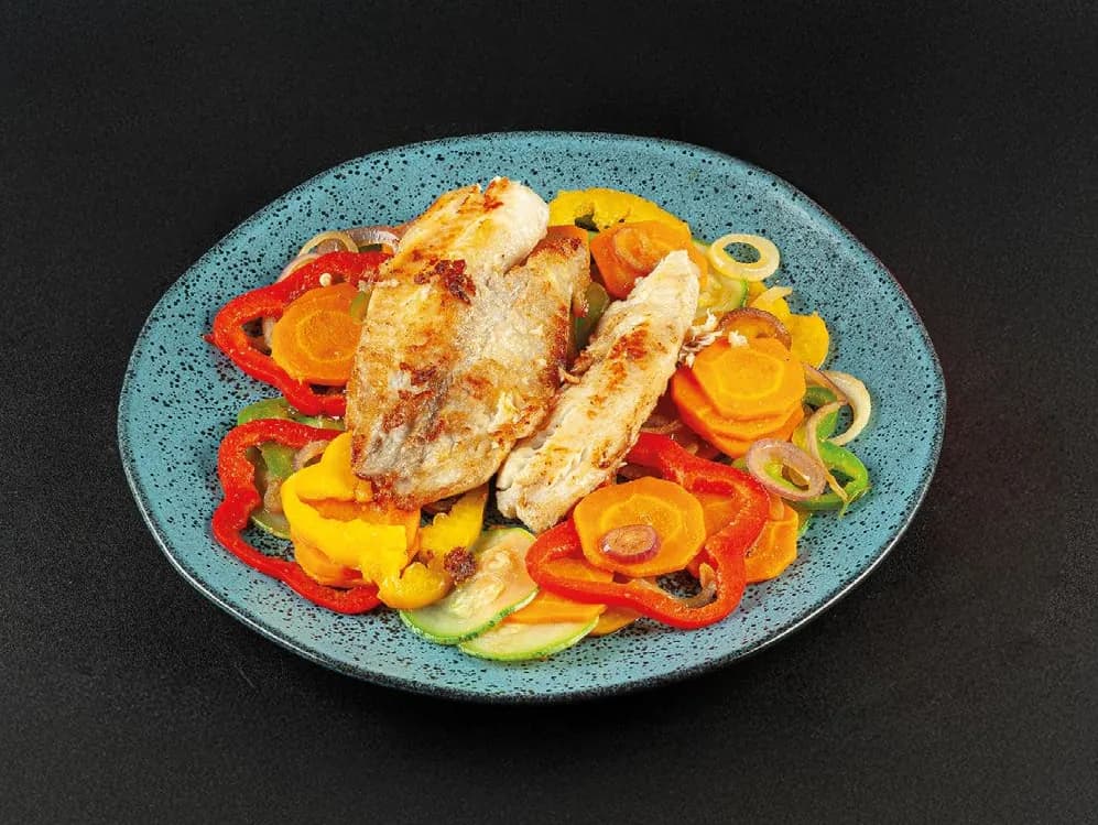 Peixe branco grelhado com legumes coloridos em prato azul